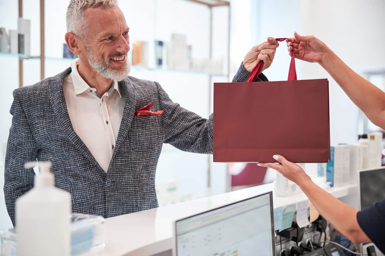 Une entrepreneure remet un sac à un client souriant, dans un local lumineux
